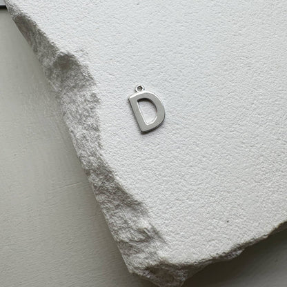 Inicialo pakabukas -  raidelė. Sidabras arba auksas