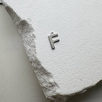 Inicialo pakabukas -  raidelė. Sidabras arba auksas